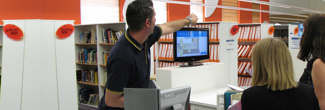 photo of a male staff member directing two female researchers in the reading room