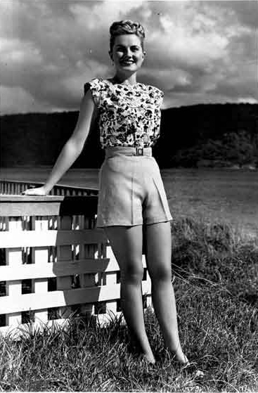 A woman wearing shorts standing and smiling at the camera